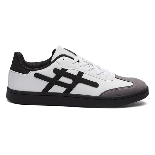 Men's low-top white sneakers featuring a grey suede toe cap, black side stripes, and a solid black flat rubber sole