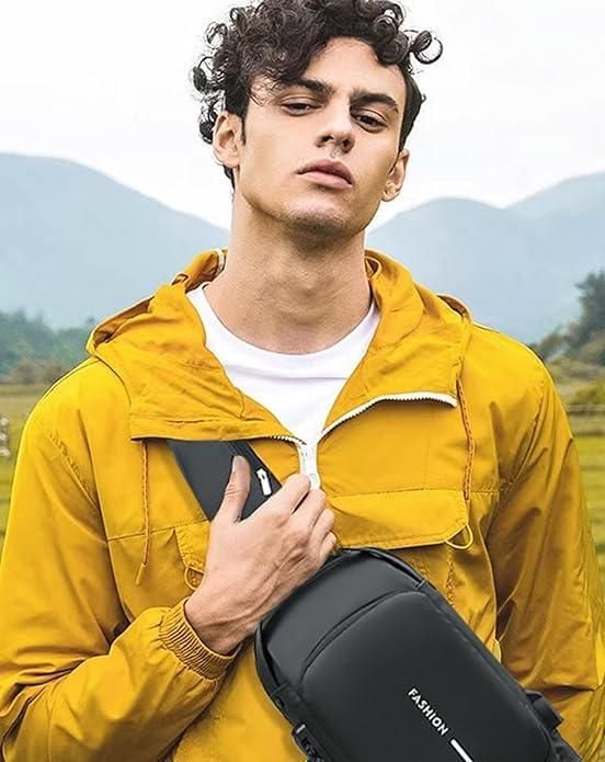 Man in yellow jacket with crossbody black sling bag posing outdoors