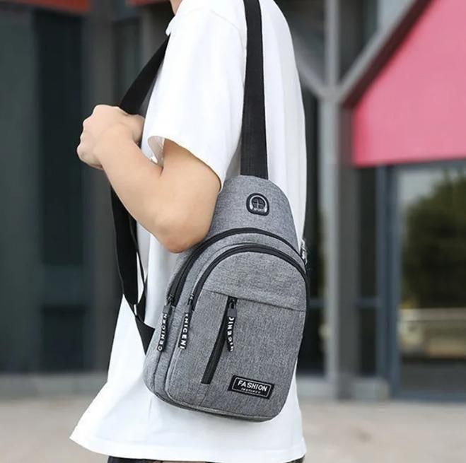 Man wearing a grey sling bag crossbody, casual street style, outdoor background