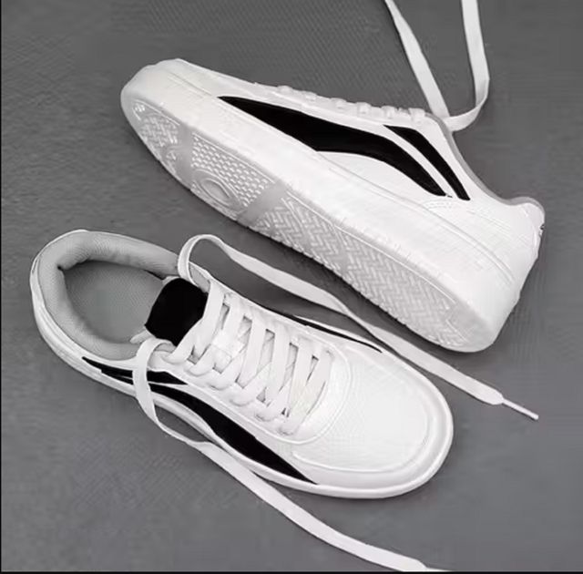 Men's white low-top sneakers with a bold black side panel, featuring flat white rubber soles