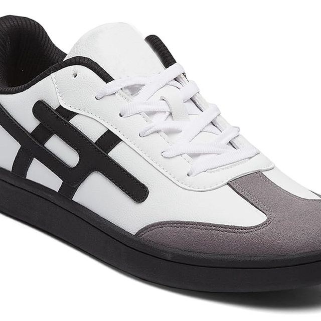 Men's low-top white sneakers featuring a grey suede toe cap, black side stripes, and a solid black flat rubber sole