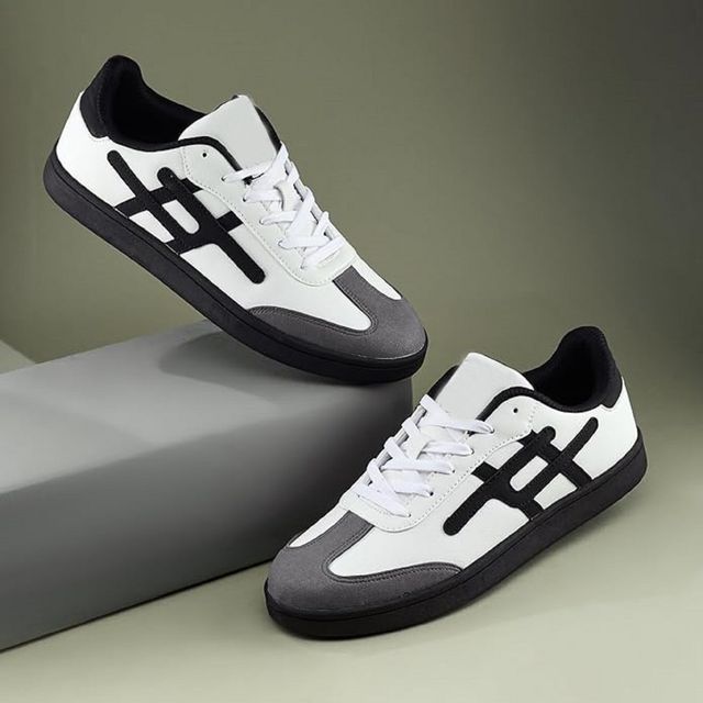 Men's low-top white sneakers featuring a grey suede toe cap, black side stripes, and a solid black flat rubber sole