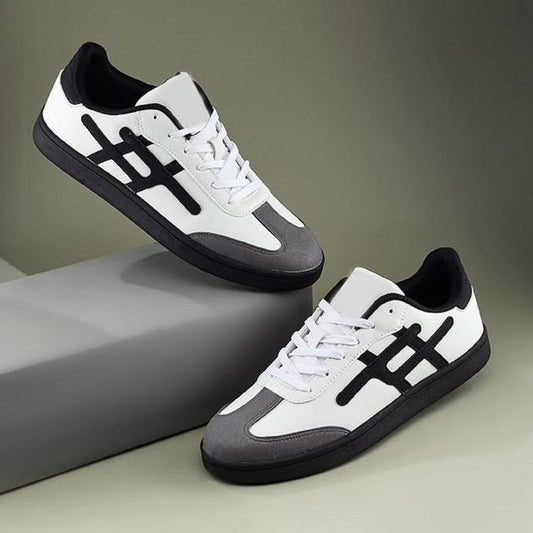 Men's low-top white sneakers featuring a grey suede toe cap, black side stripes, and a solid black flat rubber sole