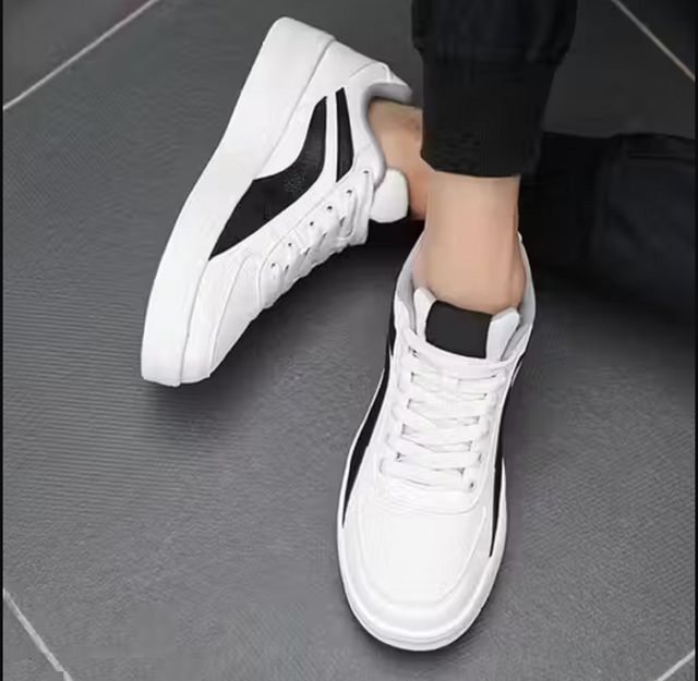 Men's white low-top sneakers with a bold black side panel, featuring flat white rubber soles