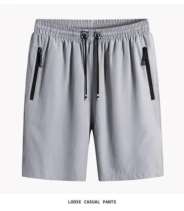 A set of four men's athletic shorts in charcoal, silver, black, and navy blue, showcasing elastic waistbands, drawstrings, and vertical zipper side pockets.