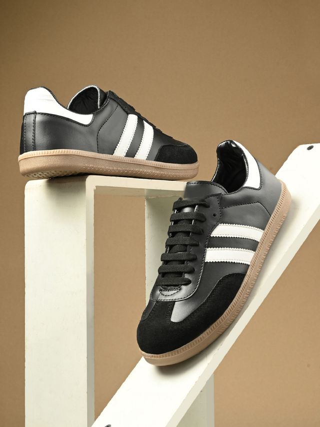 A pair of unisex black leather and suede combination retro-style sneakers featuring two prominent white side stripes, black laces